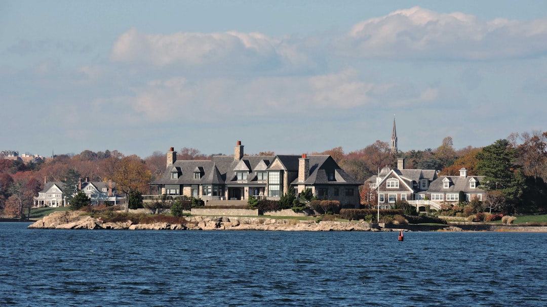 Coastal estate outdoor kitchen and pool deck with open pergola and waterfront view