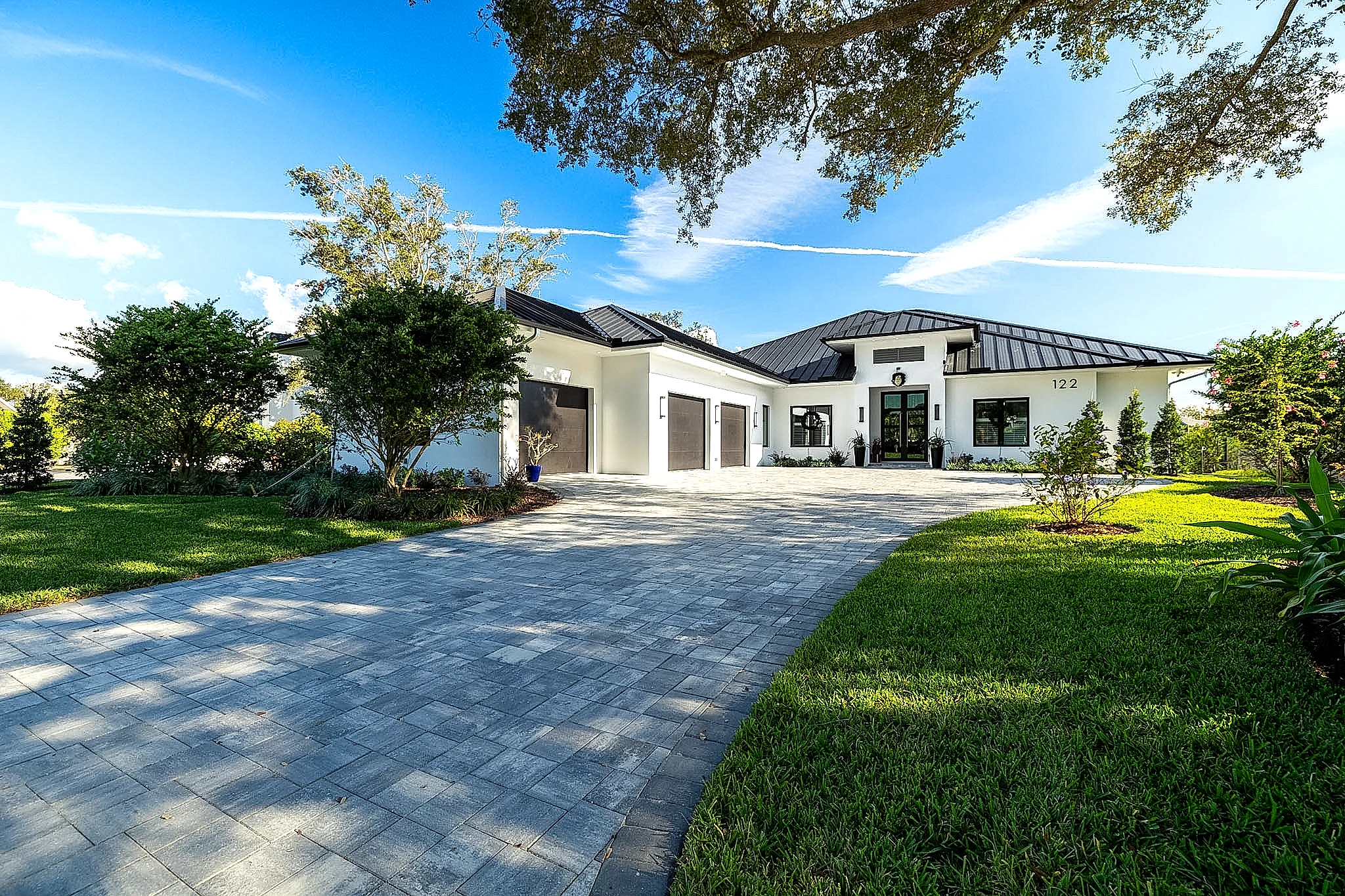 White modern estate with paver driveway and tropical landscaping — Naples