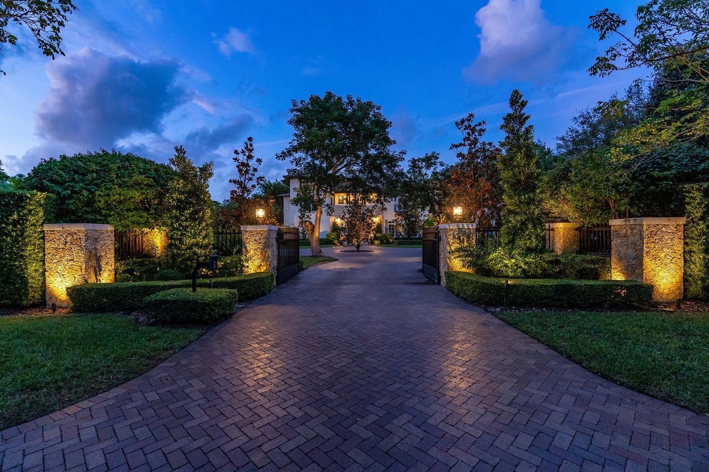 Outdoor estate at night with warm amber lighting on tropical planting and pool