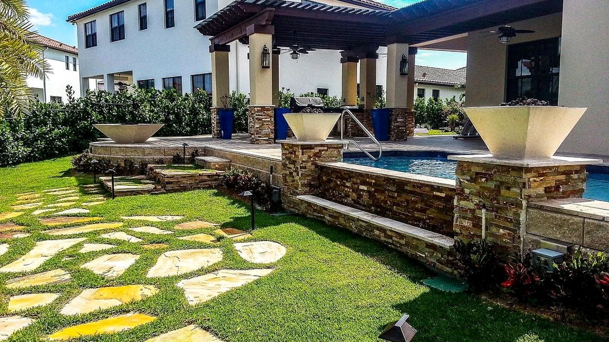 Outdoor kitchen and pool terrace integration on a Naples estate — covered entertaining room opening to the pool deck