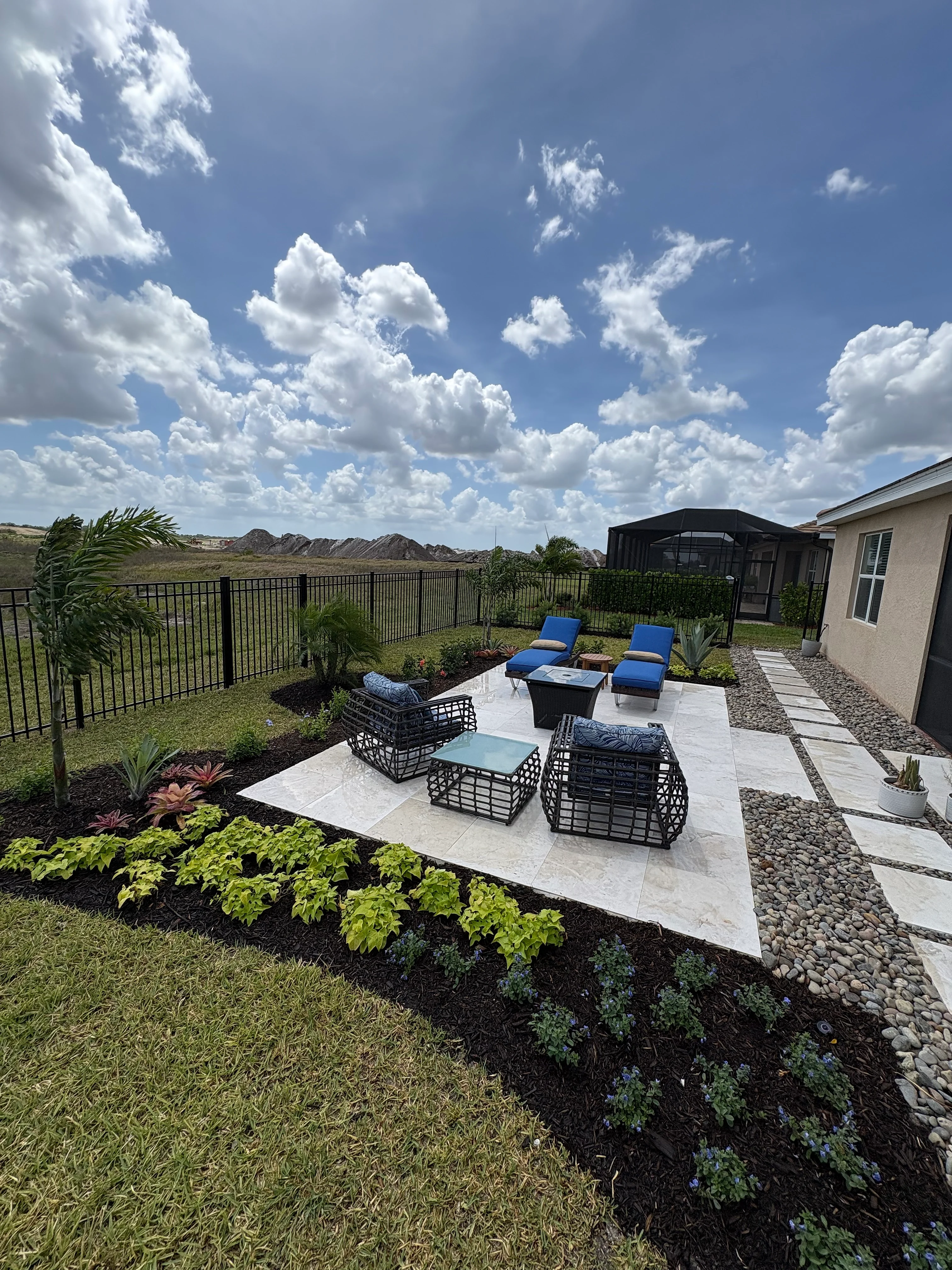 Travertine patio with outdoor seating and garden landscaping — Naples, FL